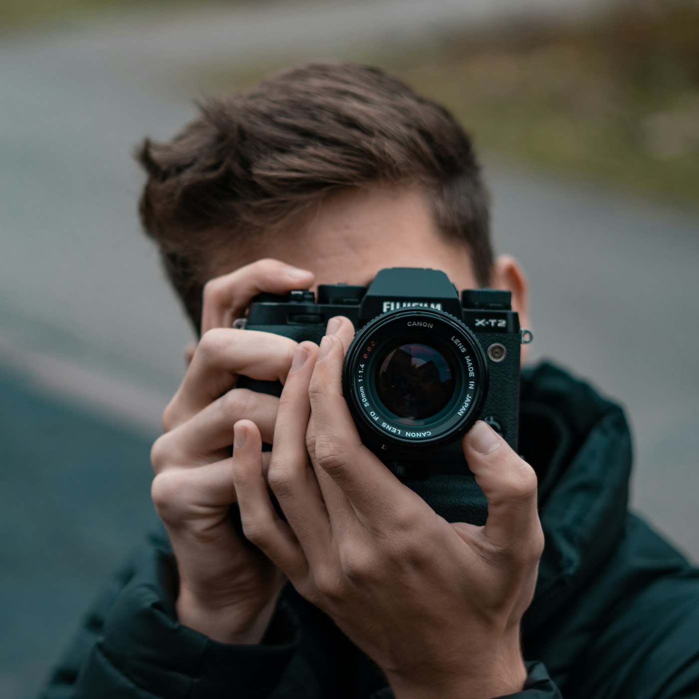 A photographer in a blue shirt holding a DSLR camera.