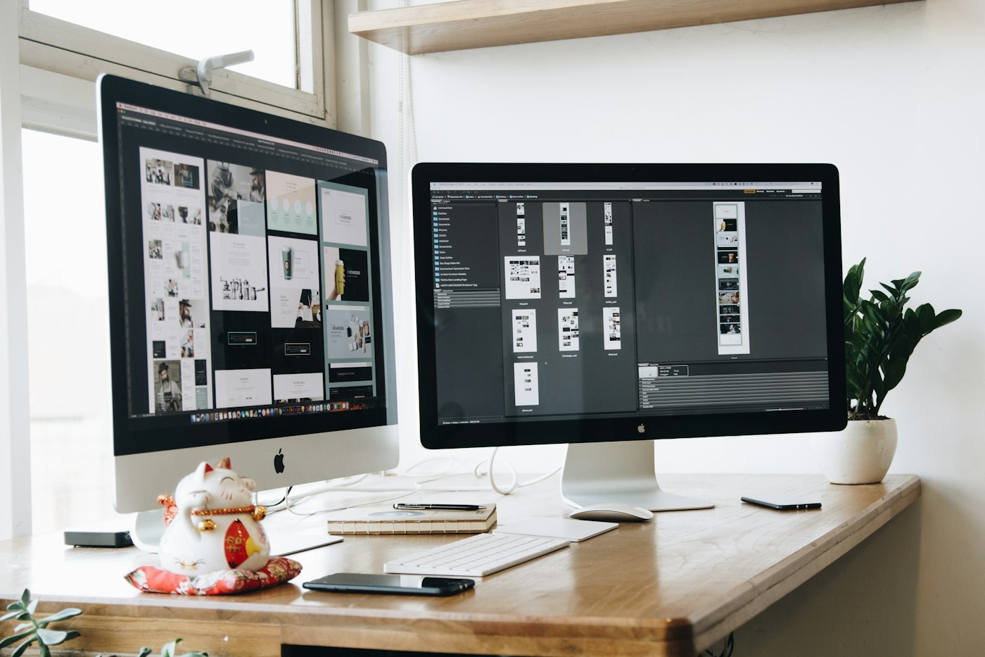 Two monitors on a wooden desk, one showing a page layout and one the editor beside it.