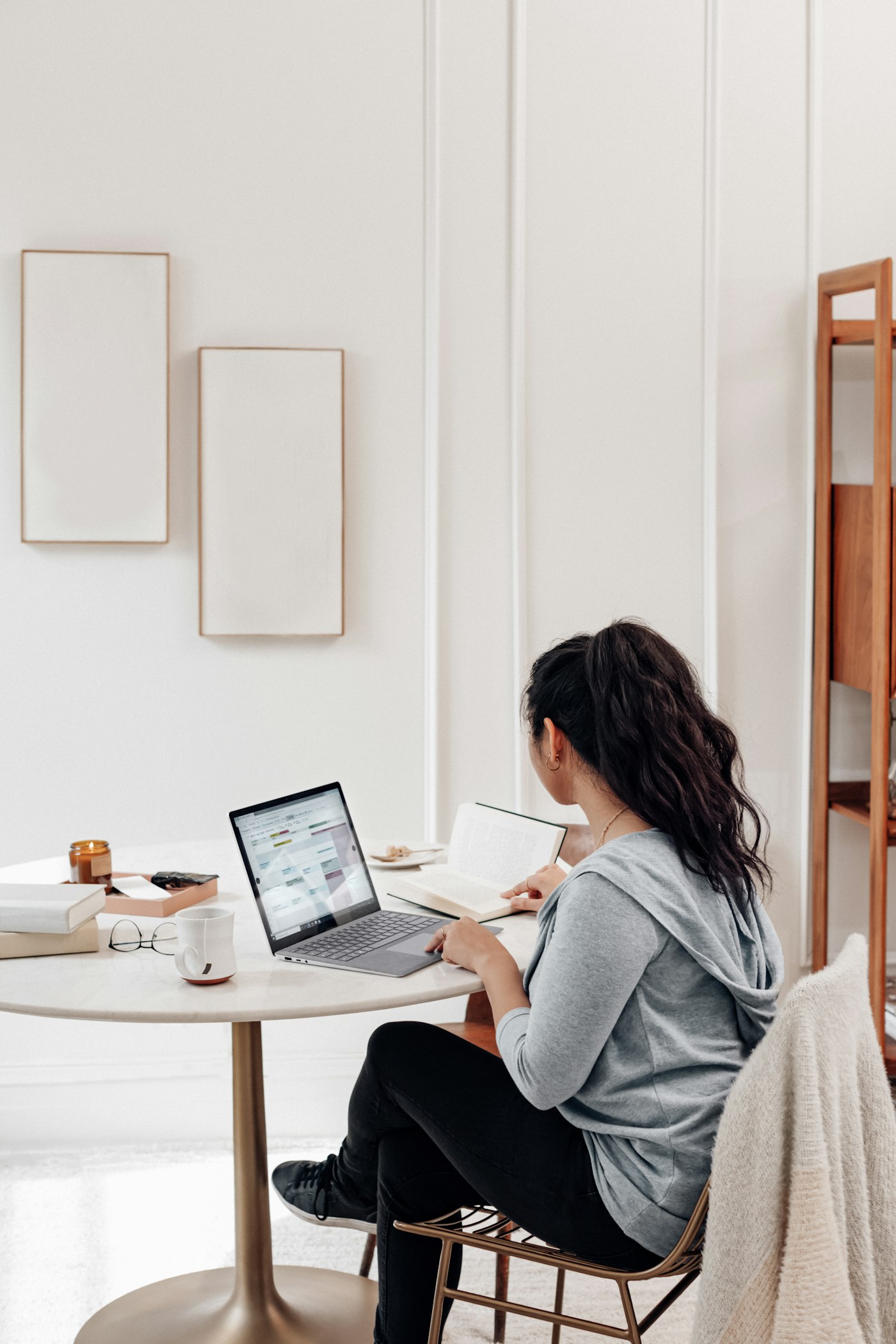 A woman filling in her details on a laptop at a bright white table.