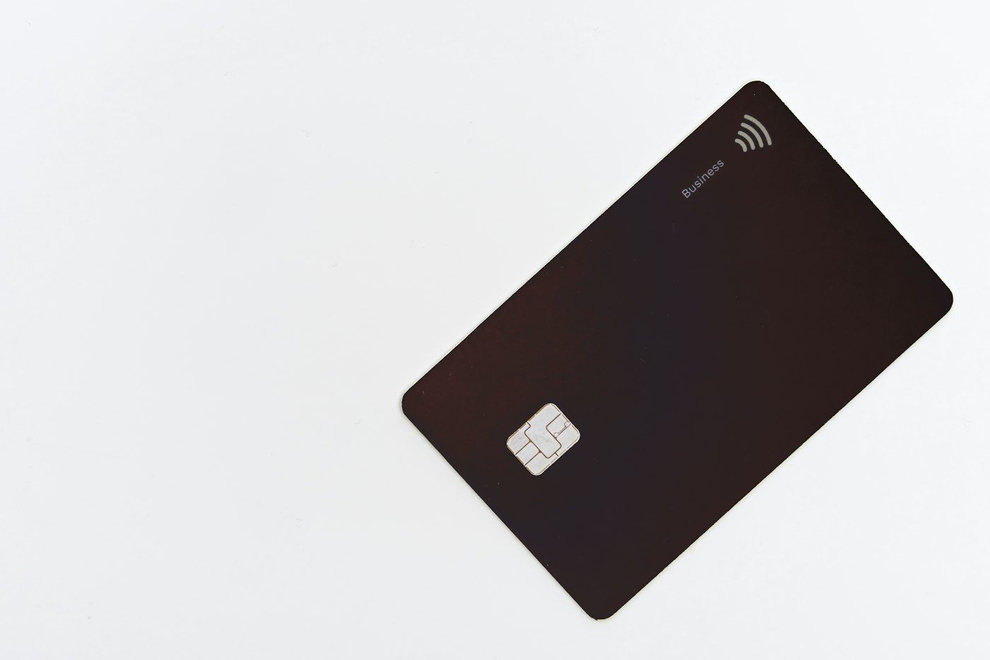 A dark smart card with a contactless chip, held in one hand.